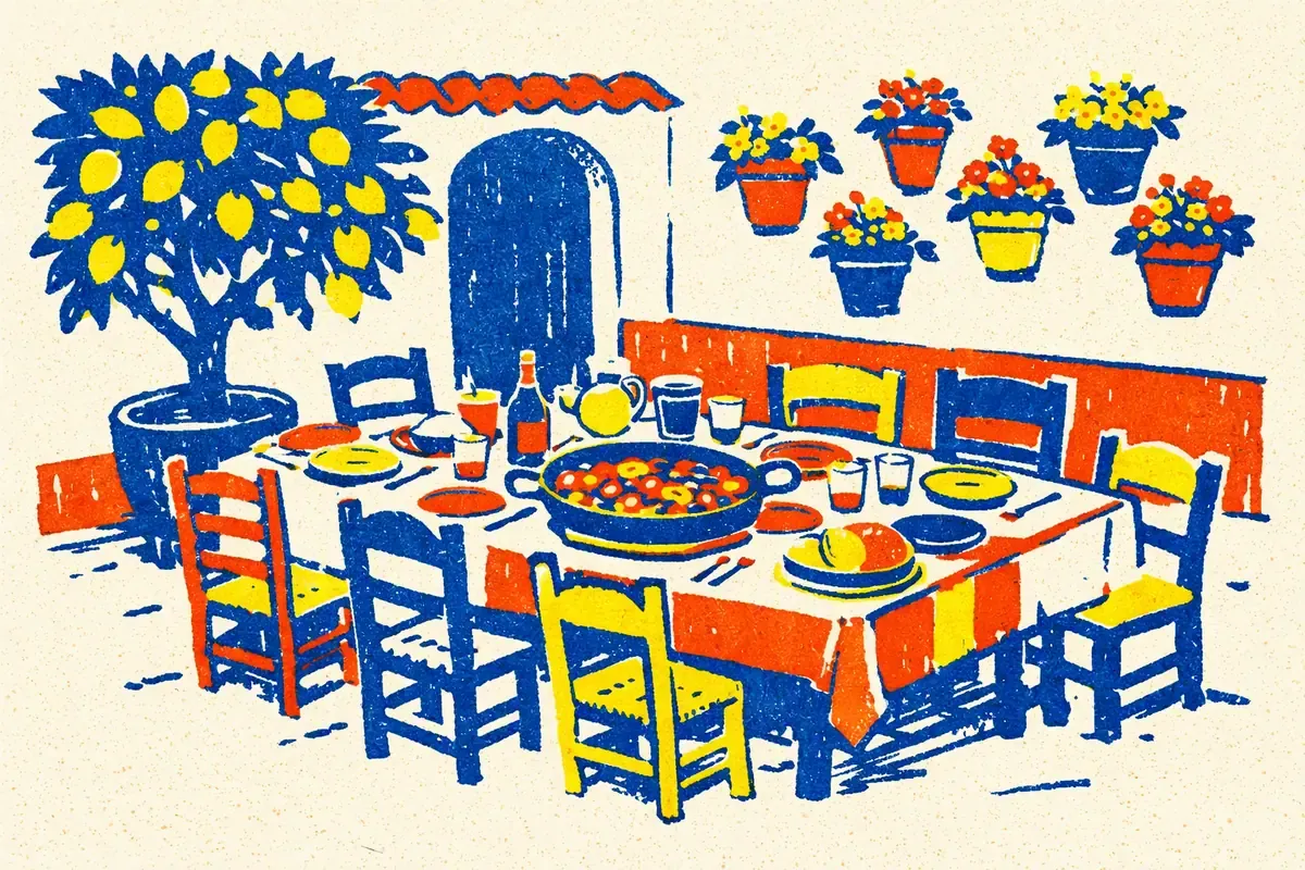 Une grande table de famille dressée dans un patio, avec un plat au centre, des chaises en bois, un citronnier et des pots de fleurs au mur, en bleu encre, rouge tomate et jaune.